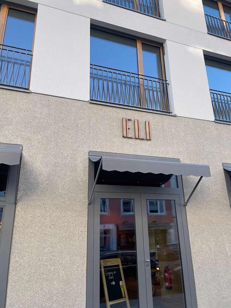 eli-schwabing_h2 Eingangstür des Restaurant ELI Schwabing mit ELI-Logo an der Fassade.