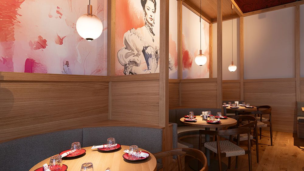 eli-schwabing_q2 Sitzbereich im Restaurant ELI Schwabing mit runden Tischen, Wandgestaltung und Pendelleuchten.