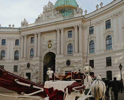 Pferdekutsche vor historischer Schlossfassade in Wien als stimmungsvolles Motiv für das Kaiserliche Dinner.