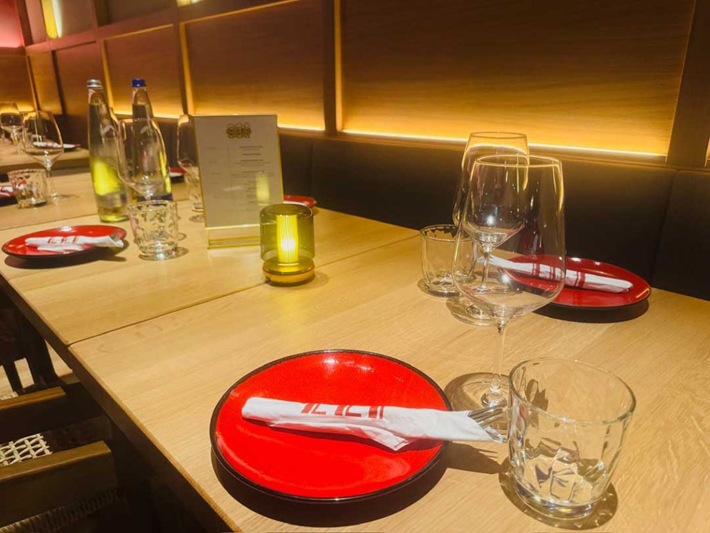 Eingedeckte Veranstaltungstafel im Restaurant ELI Schwabing mit Kerzenlicht, Gläsern und Menükarten.