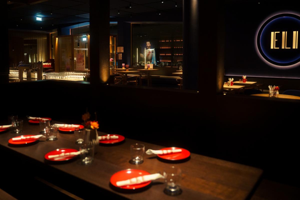 Lange gedeckte Tafel mit Blick auf den Restaurant- und Barbereich des ELI Schwabing.