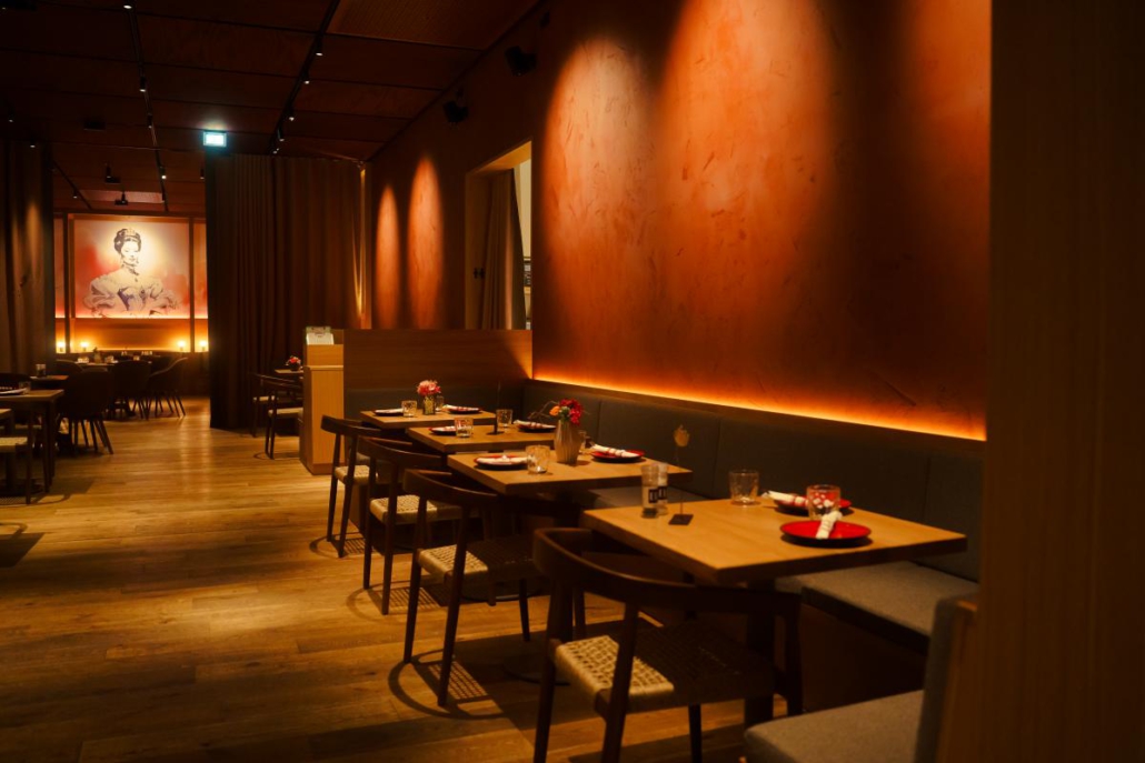 Restaurantbereich mit warm beleuchteter Wandgestaltung und gedeckten Tischen.